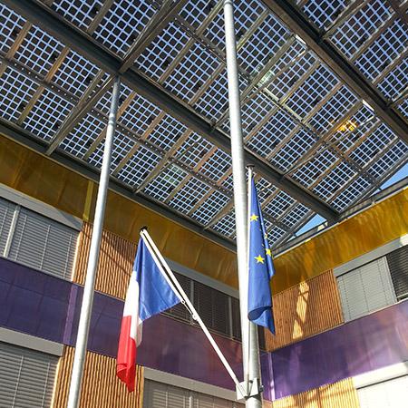 Le drapeau de la France et de l'union européenne accrochés sous la verrière de panneaux solaires